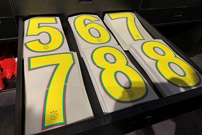 Rugnummers liggen klaar om op shirts te worden geperst. © Ajax Life