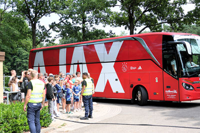 De rode spelersbus van Ajax rolt het terrein op. © SV Ajax